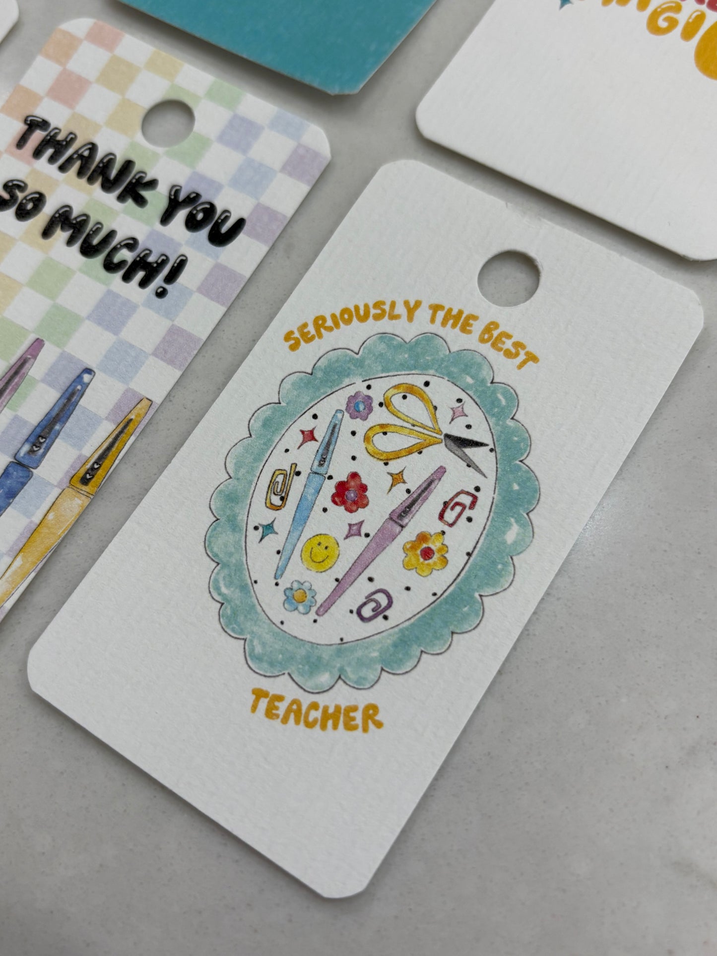 Decorative gift tag for a teacher with stationery icons and 'Thank you so much!'  and 'seriously the best teacher' text on a gray background.
