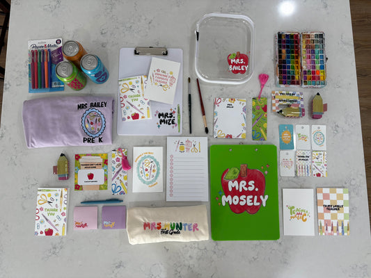 Collection of stationery supplies and personalized items on a white surface