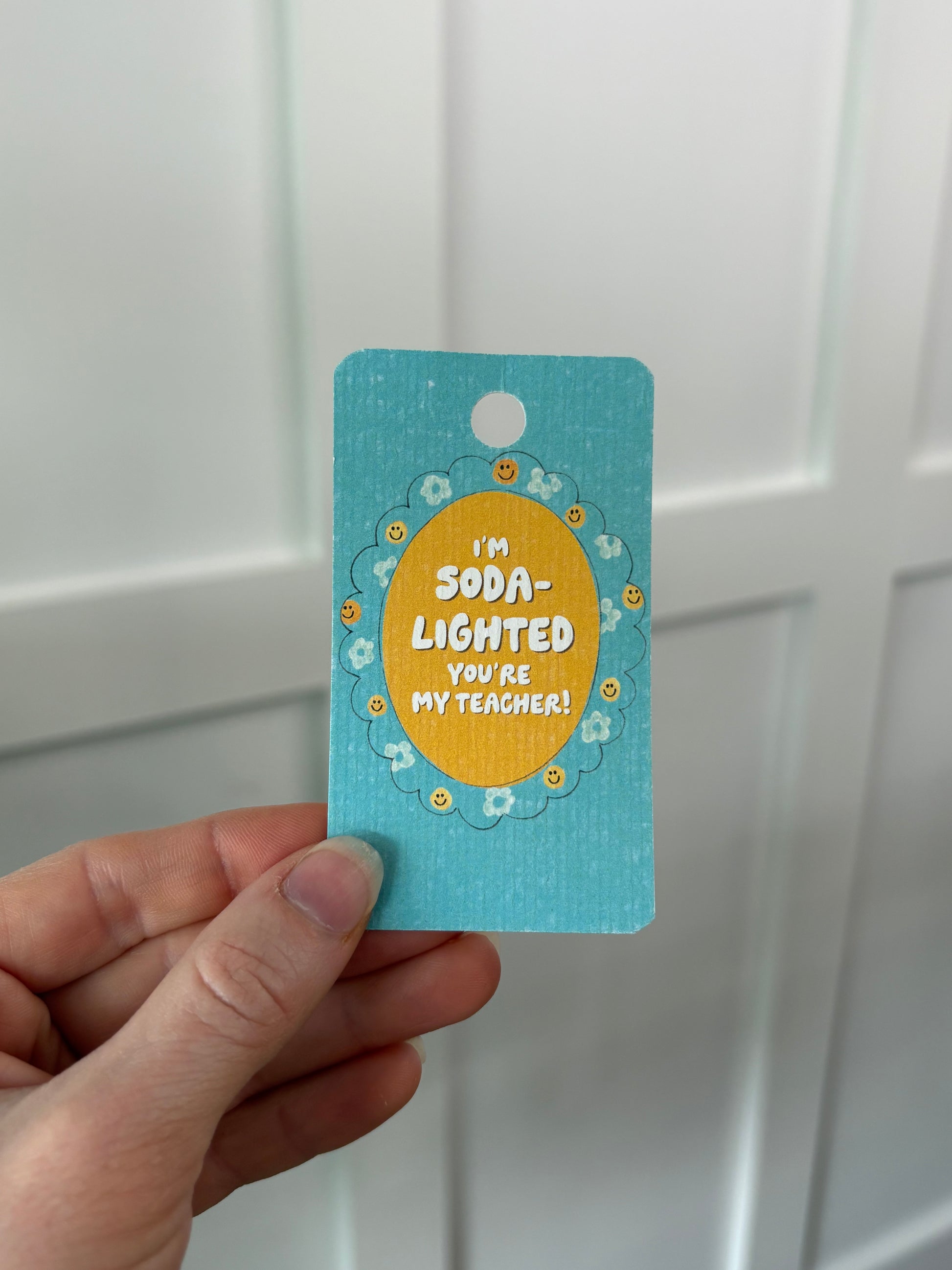 Hand holding a blue gift tag with yellow text against a white background