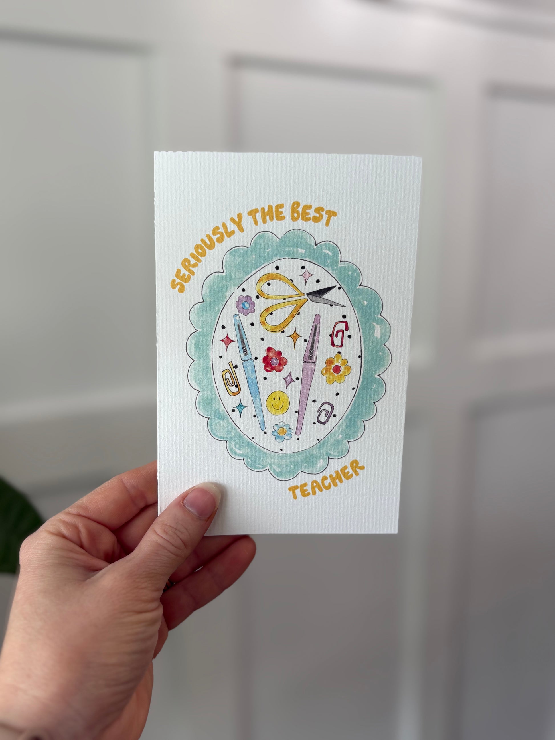 Hand holding a card with decorative elements and text on a neutral background