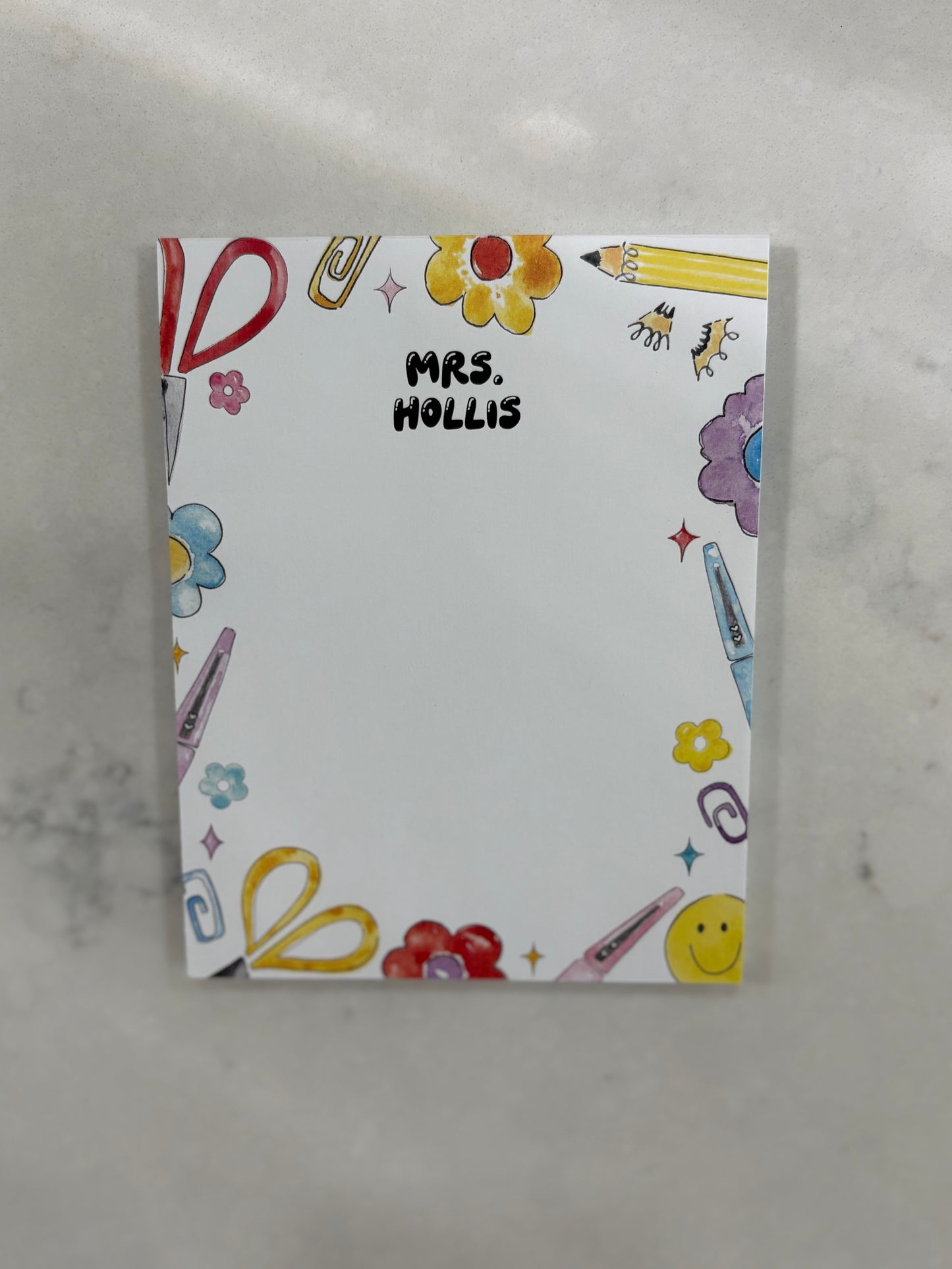 Notebook with colorful illustrations and 'Mrs. Hollis' text on a gray background