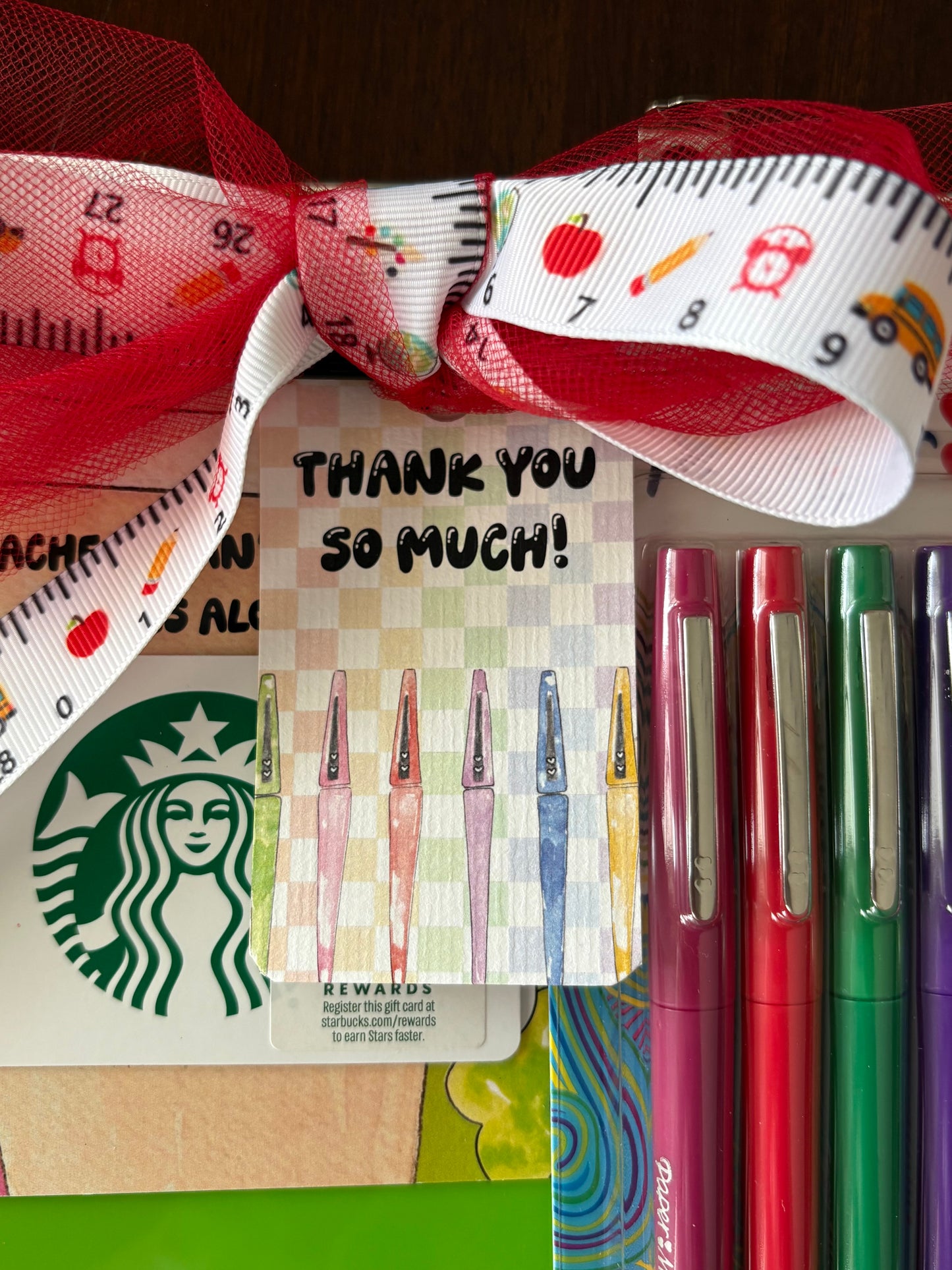 Colorful pens with a 'Thank you so much!' gift tag  and Starbucks gift card, tied with a decorative ribbon.