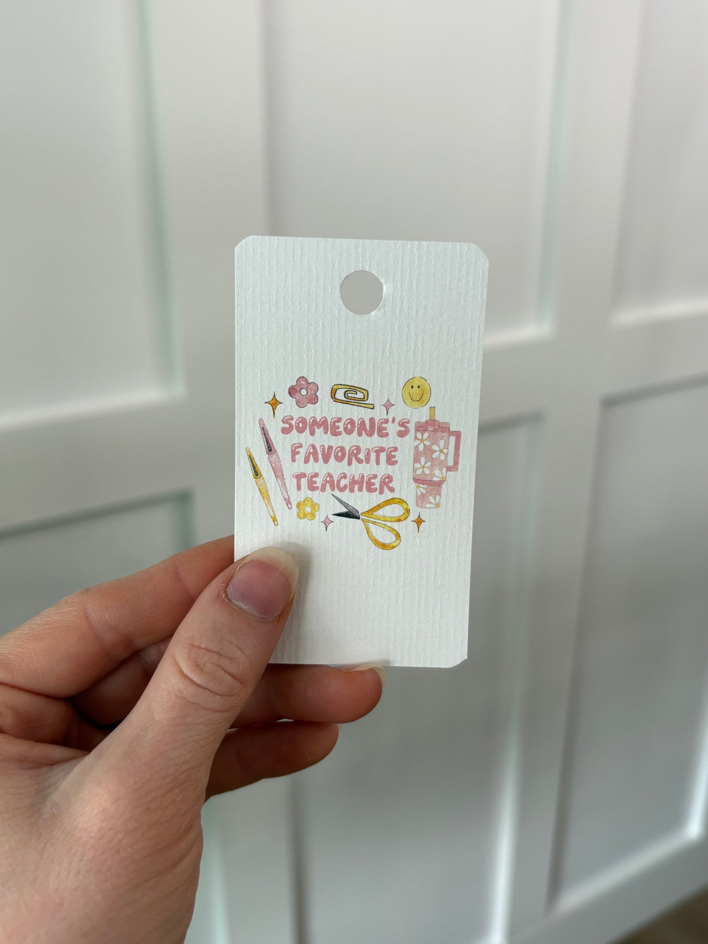 Hand holding a white tag with text and graphics against a white background