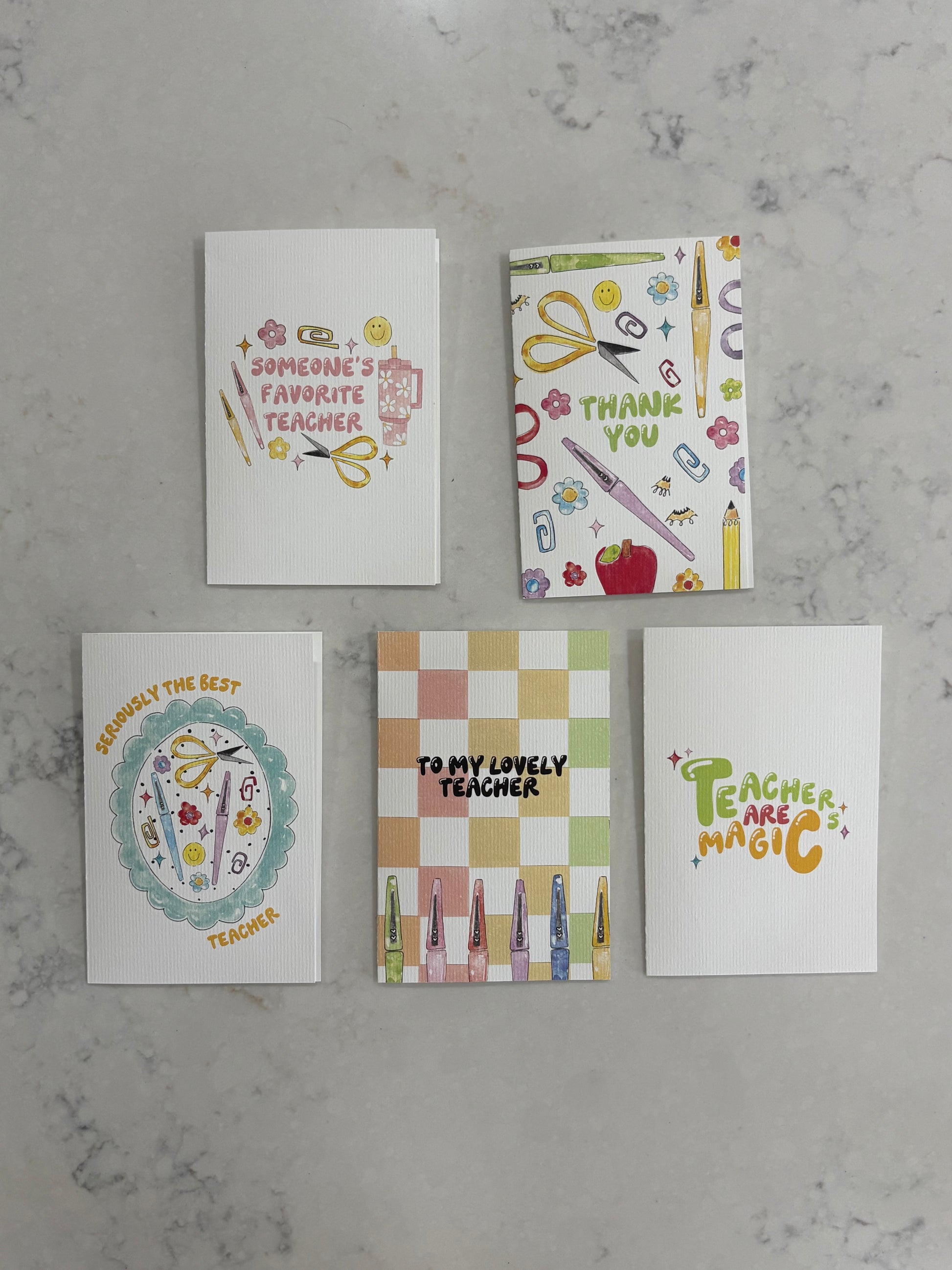 Five greeting cards with various designs on a gray surface