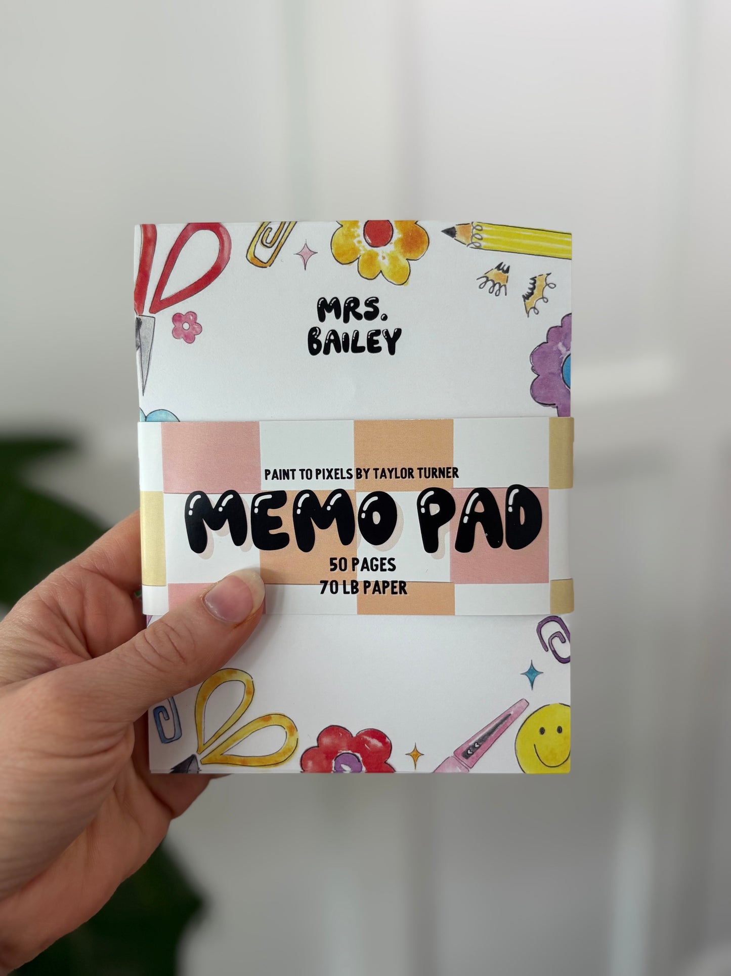 Memo pad with colorful design held by a hand against a neutral background