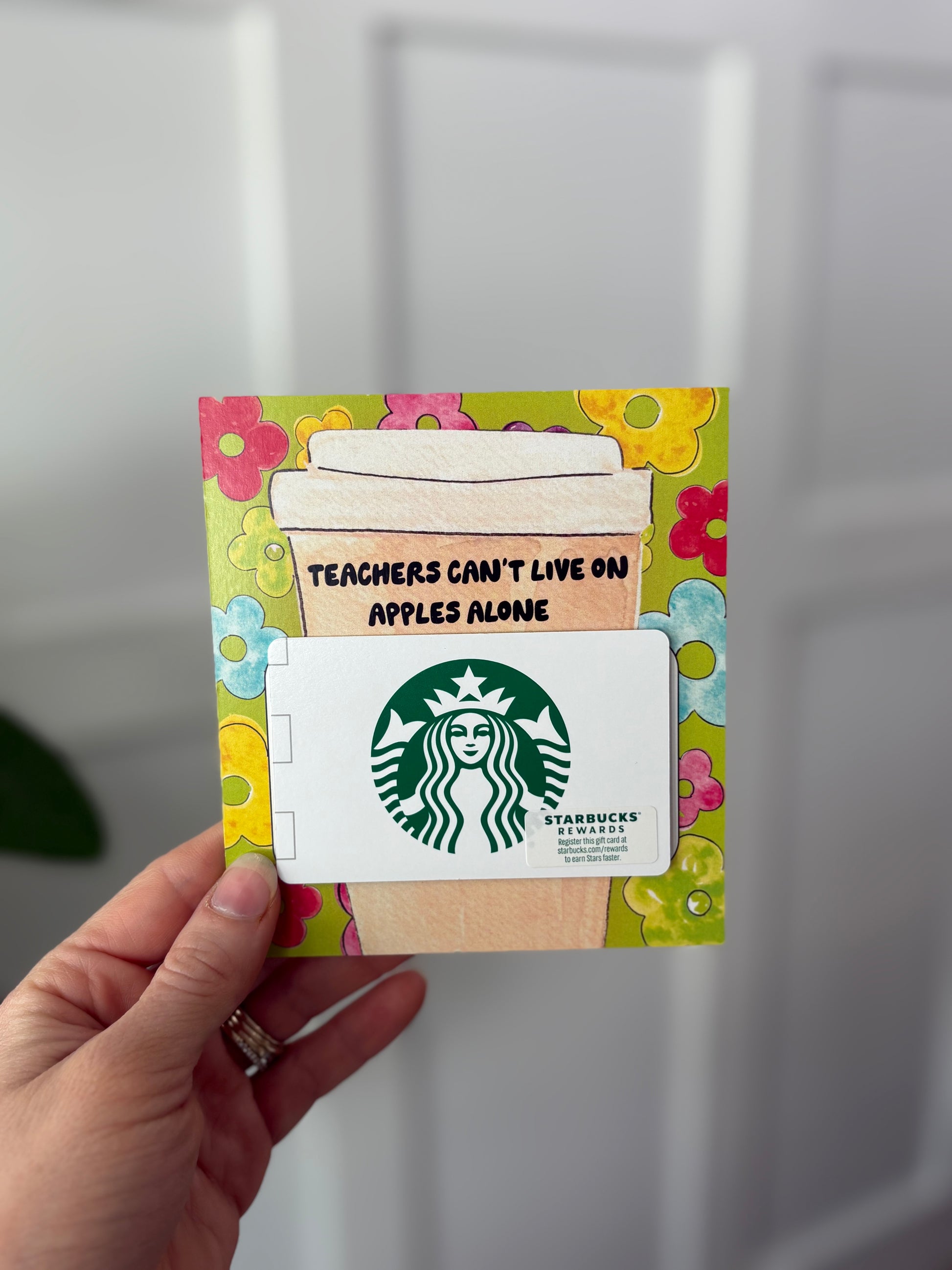 Starbucks gift card with decorative holderheld by a hand against a neutral background
