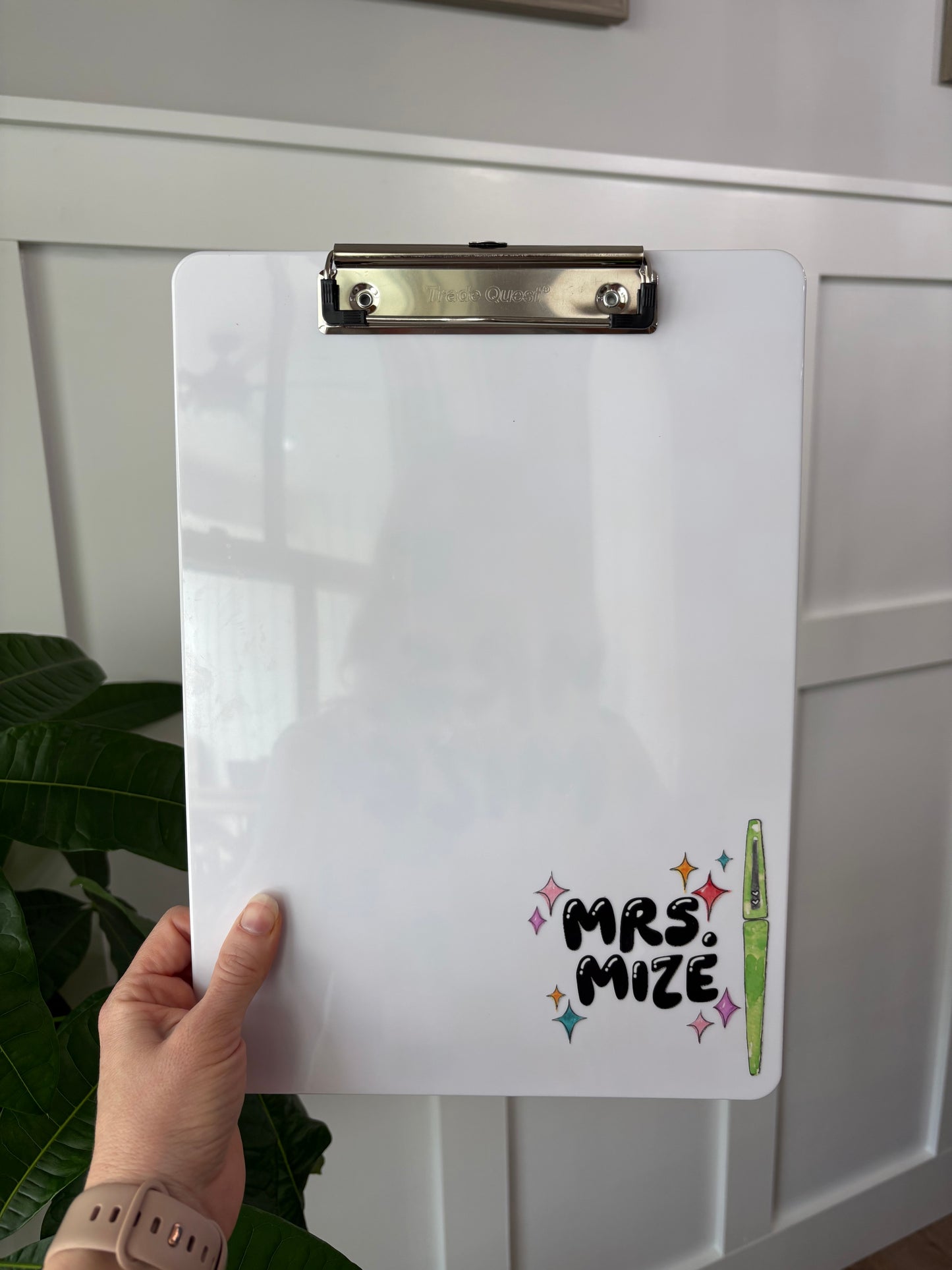 White clipboard with 'Mrs. Mize' branding held by a person against a light-colored wall.