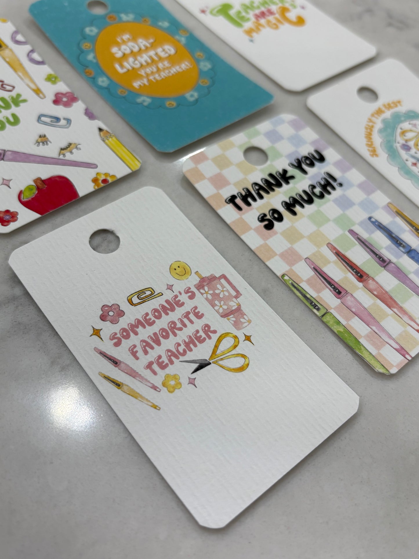 Collection of colorful gift tags with various designs on a gray surface