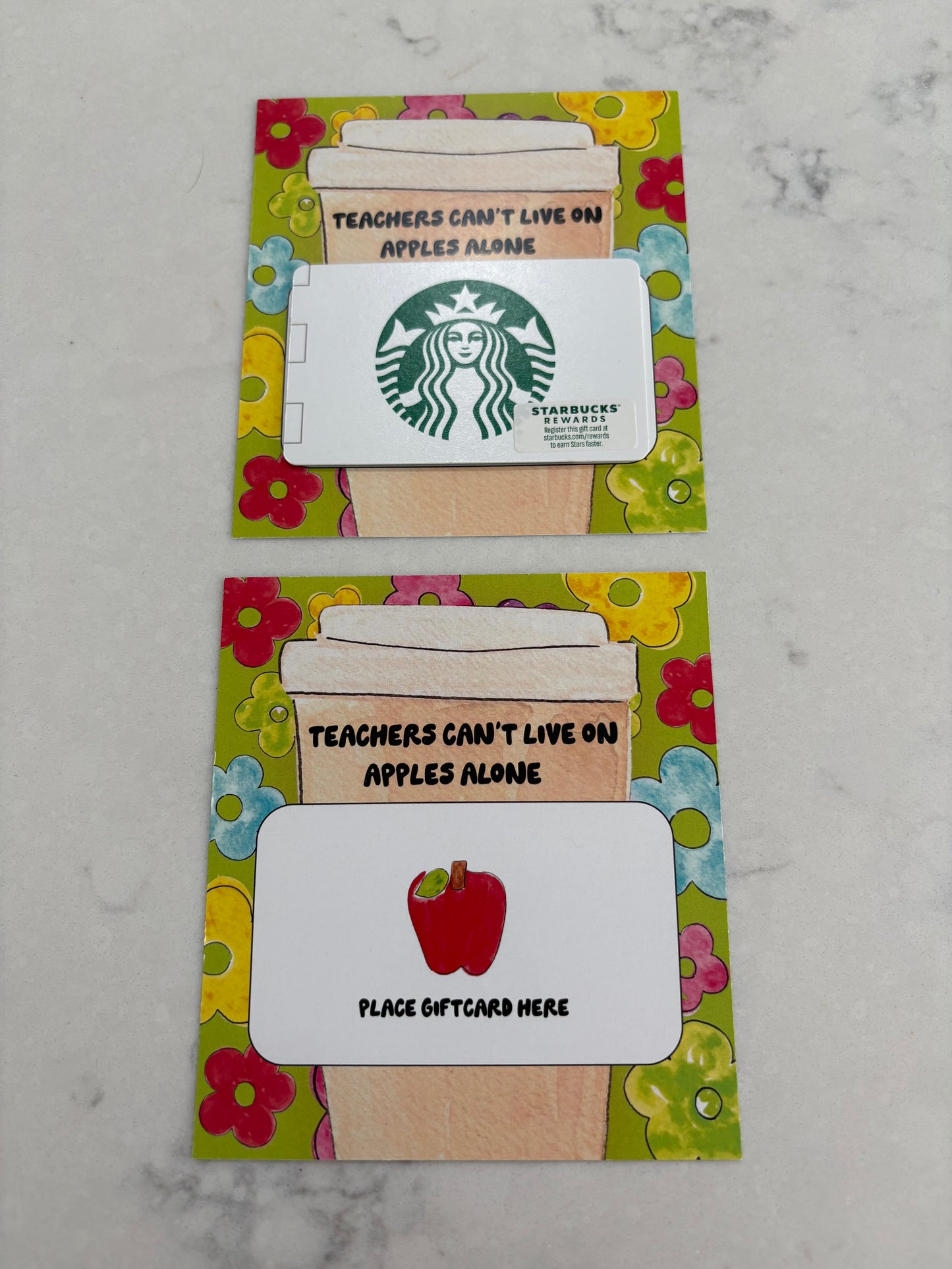 Two decorative gift card holders with colorful borders and text on a marble surface