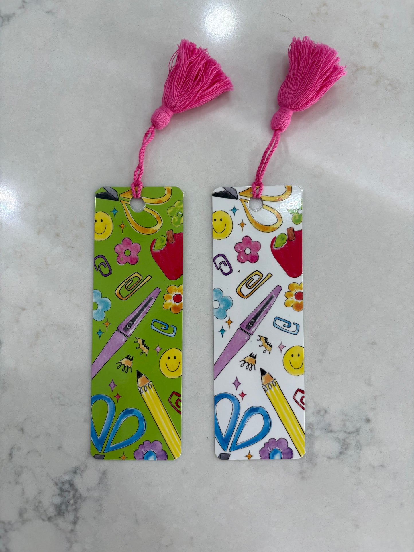 Two colorful bookmarks with tassels on a marble surface