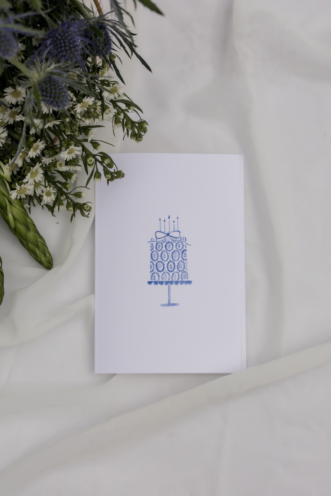 White card with blue design on a white fabric background