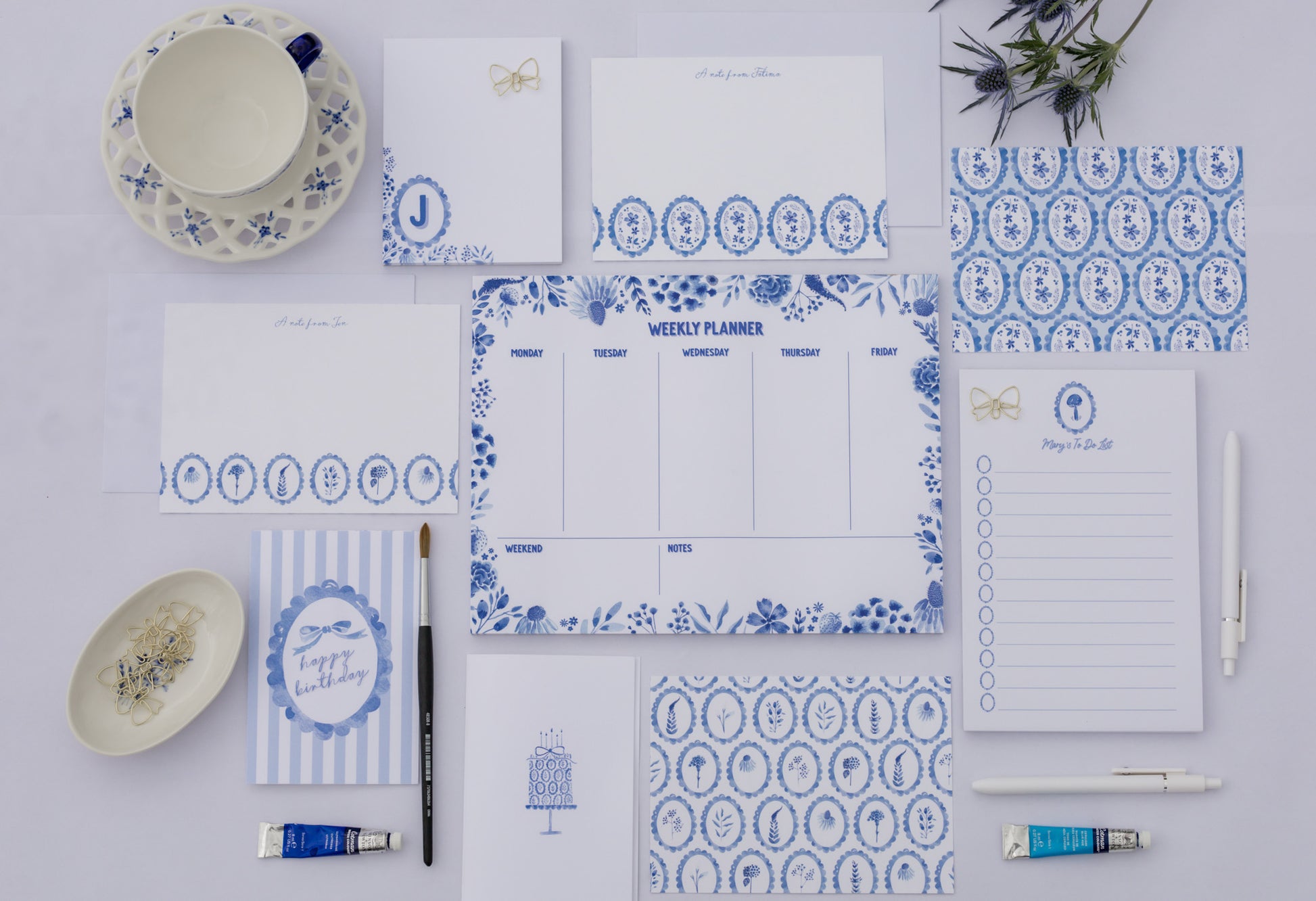 Collection of blue and white patterned stationery items on a light gray background