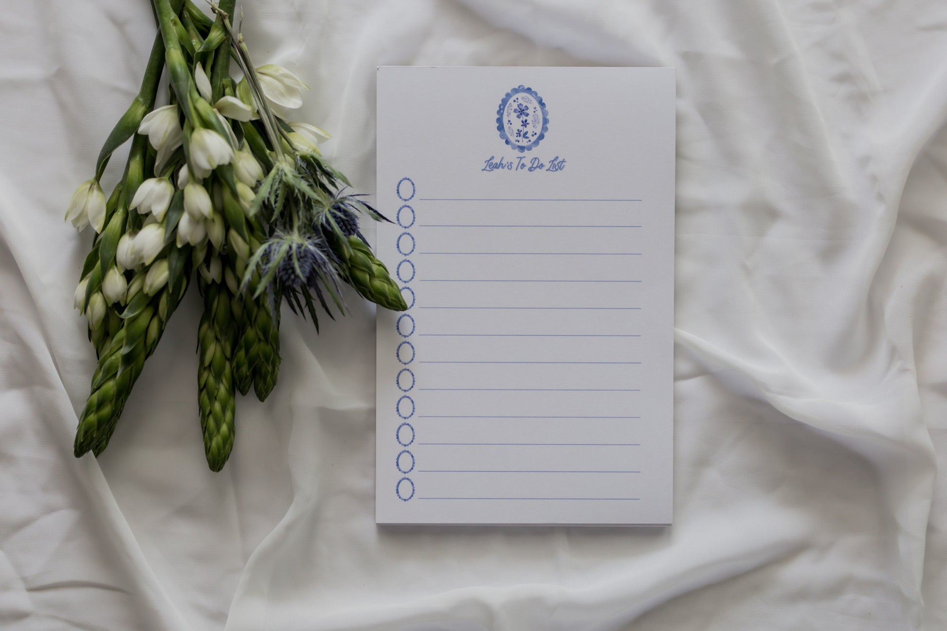 Notepad with floral arrangement on a white fabric background