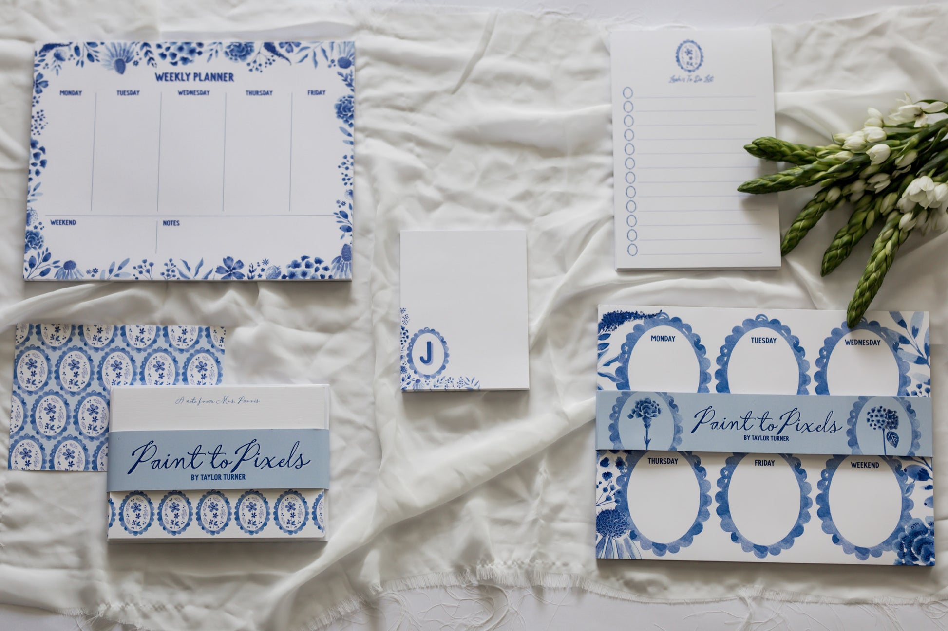 Set of blue and white stationery items on a textured surface with 'Paint to Pixels' branding.
