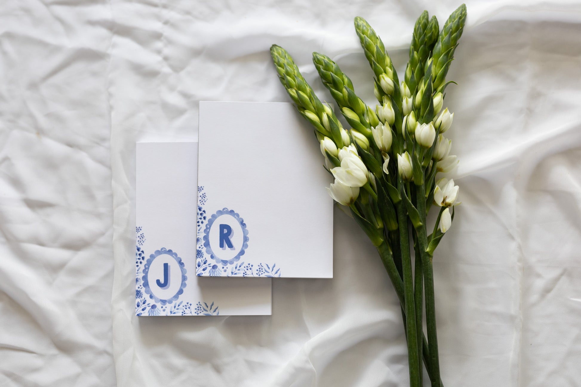 memo pads with initials and floral design on a white fabric background