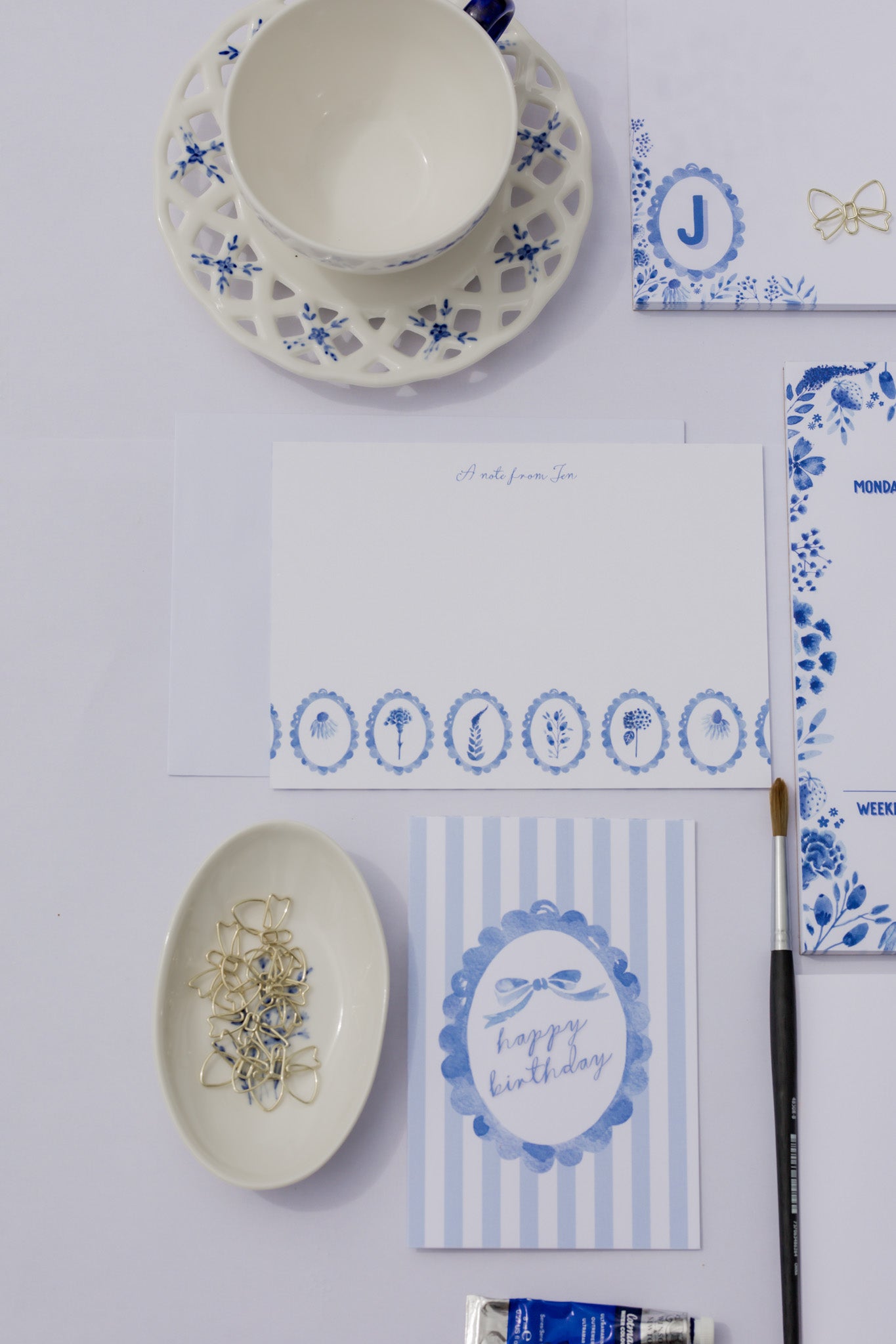Table setting with blue and white stationery including a bowl, plates, and cards.