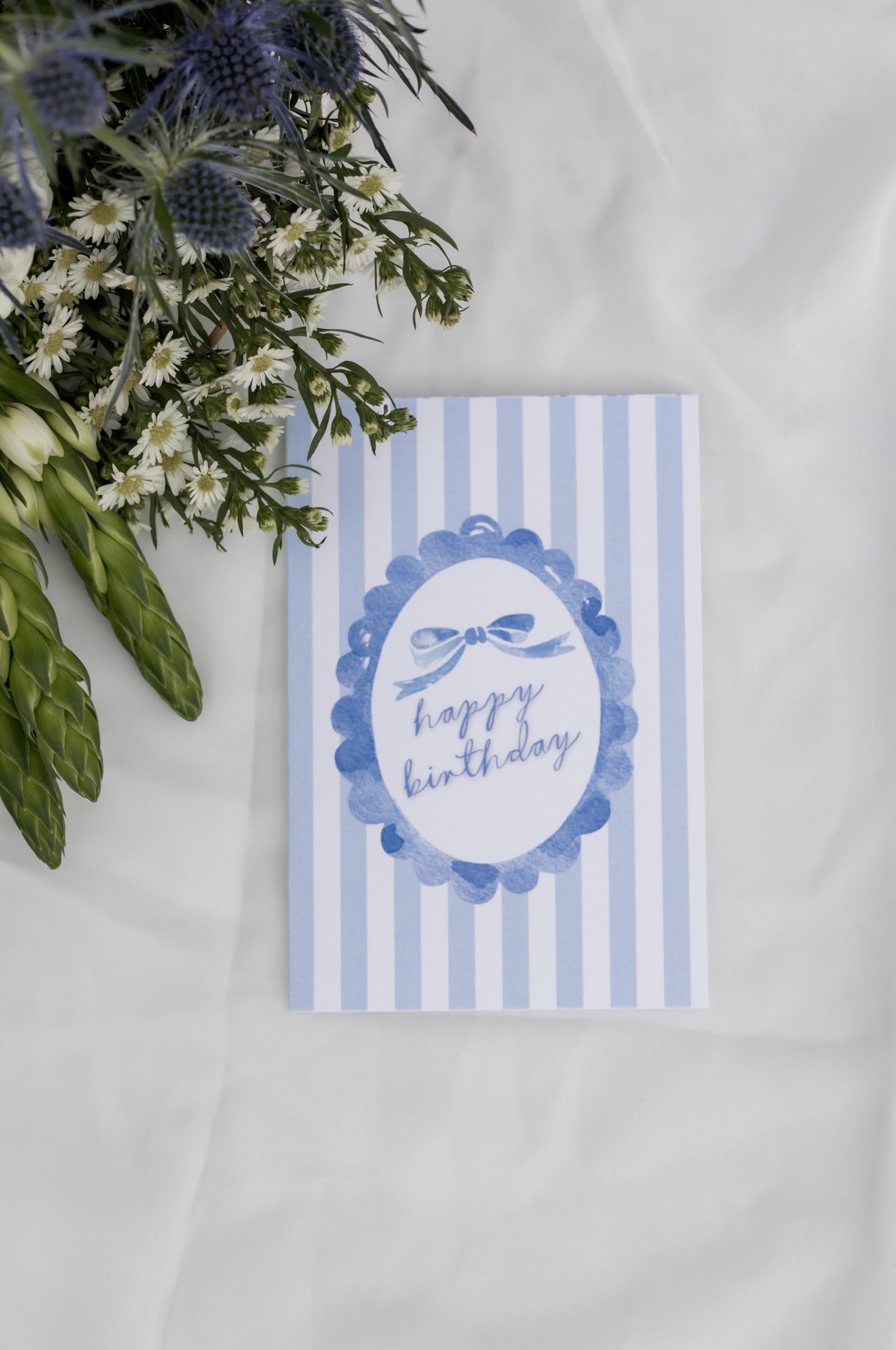 Blue striped birthday card with floral arrangement on a white background