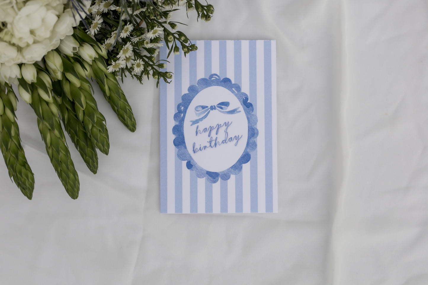 Blue and white striped birthday card with floral arrangement on a white background