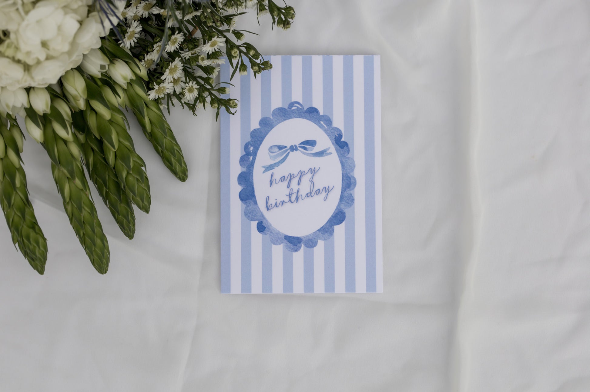 Blue and white striped birthday card with floral arrangement on a white background