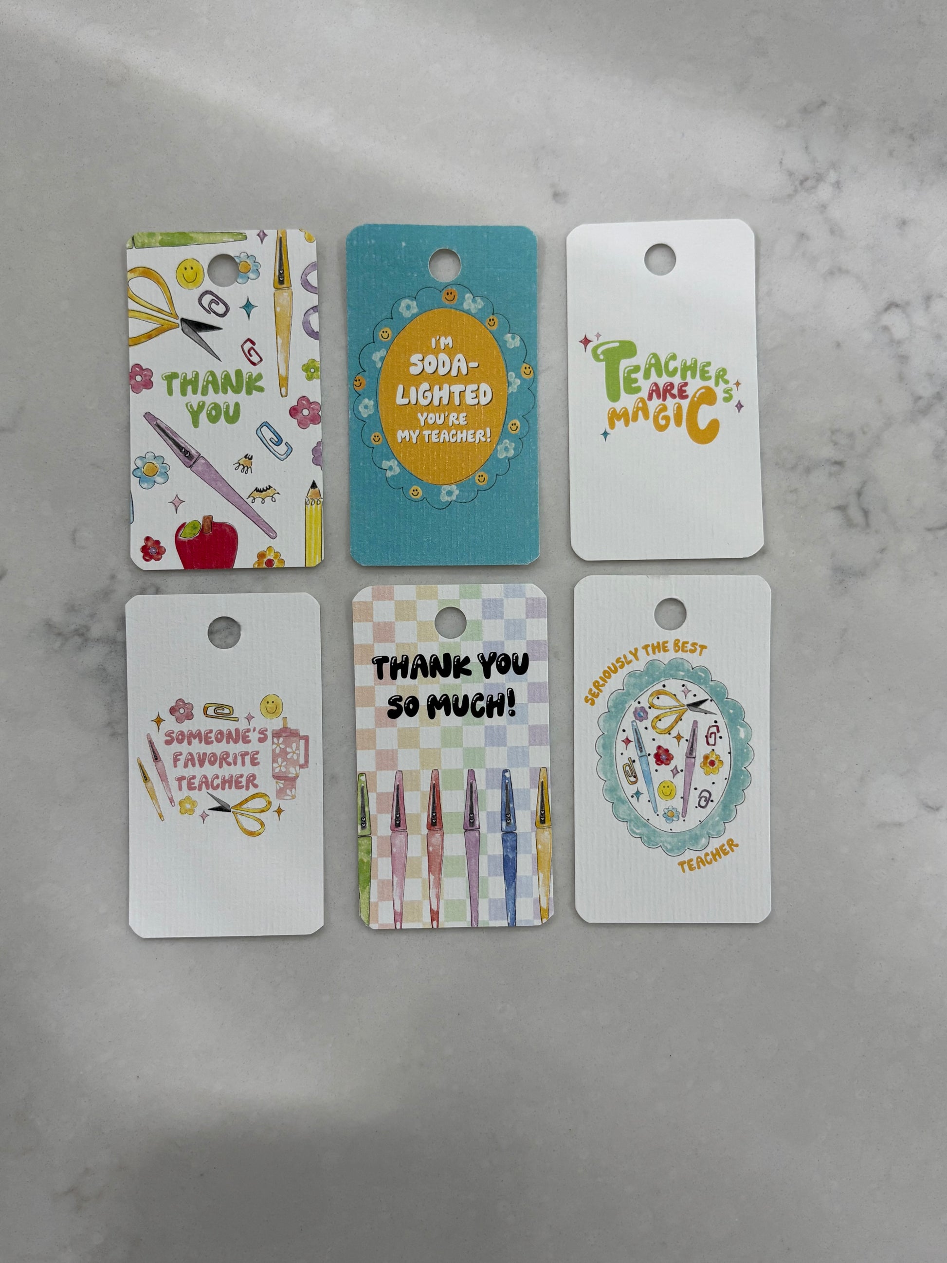Set of six colorful gift tags with teacher-themed designs on a gray surface