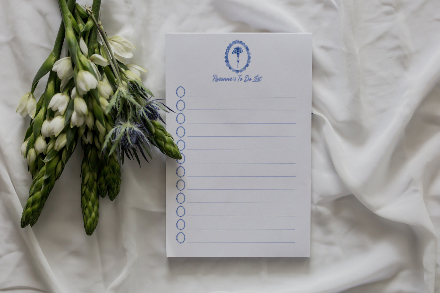 Notepad with a floral arrangement on a white fabric background