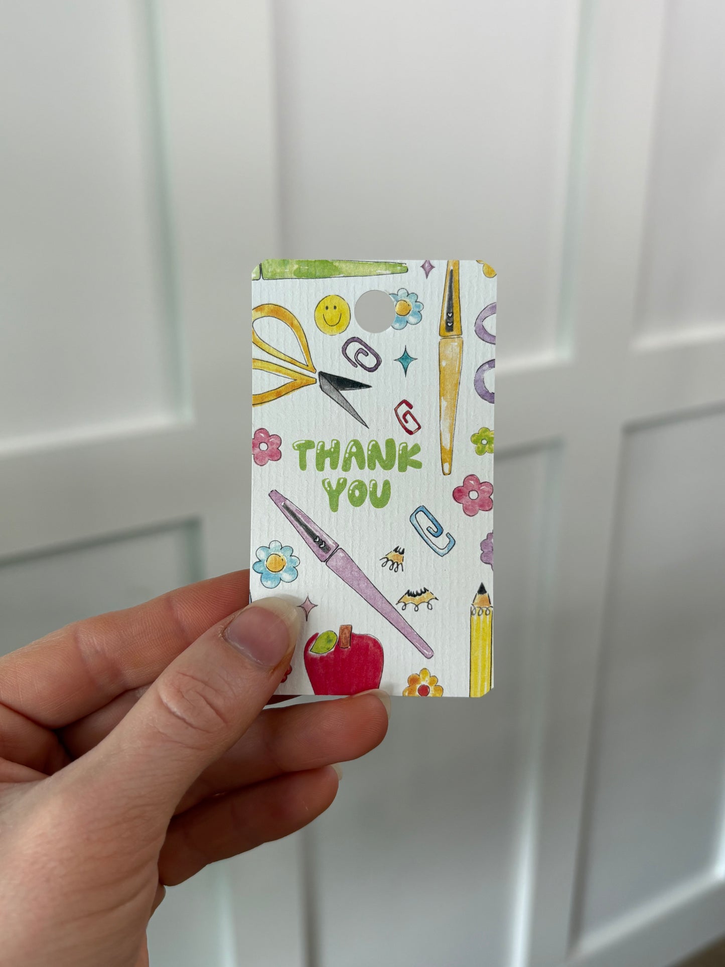 Hand holding a small gift tag with  'Thank You' text against a white background 