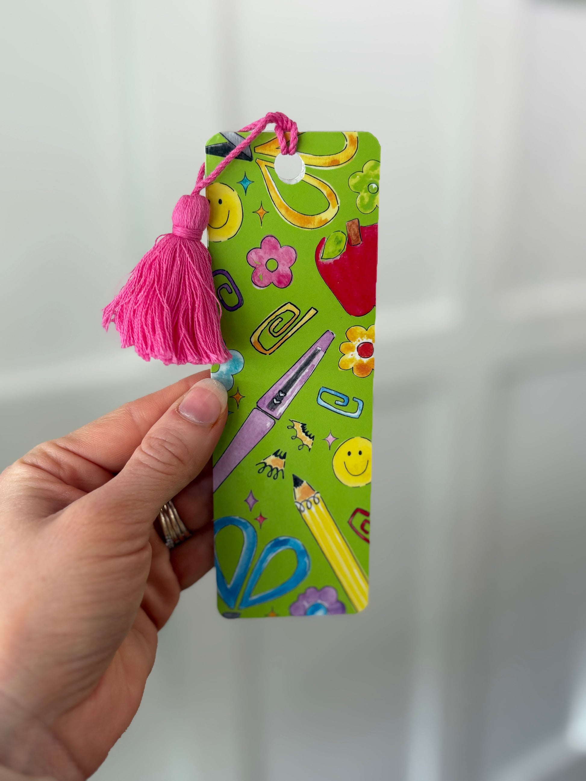 Colorful bookmark with tassel held by a hand against a white background