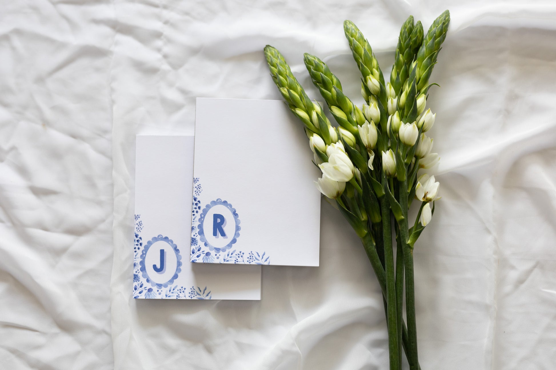 memo pads with initials and floral design on a white fabric background