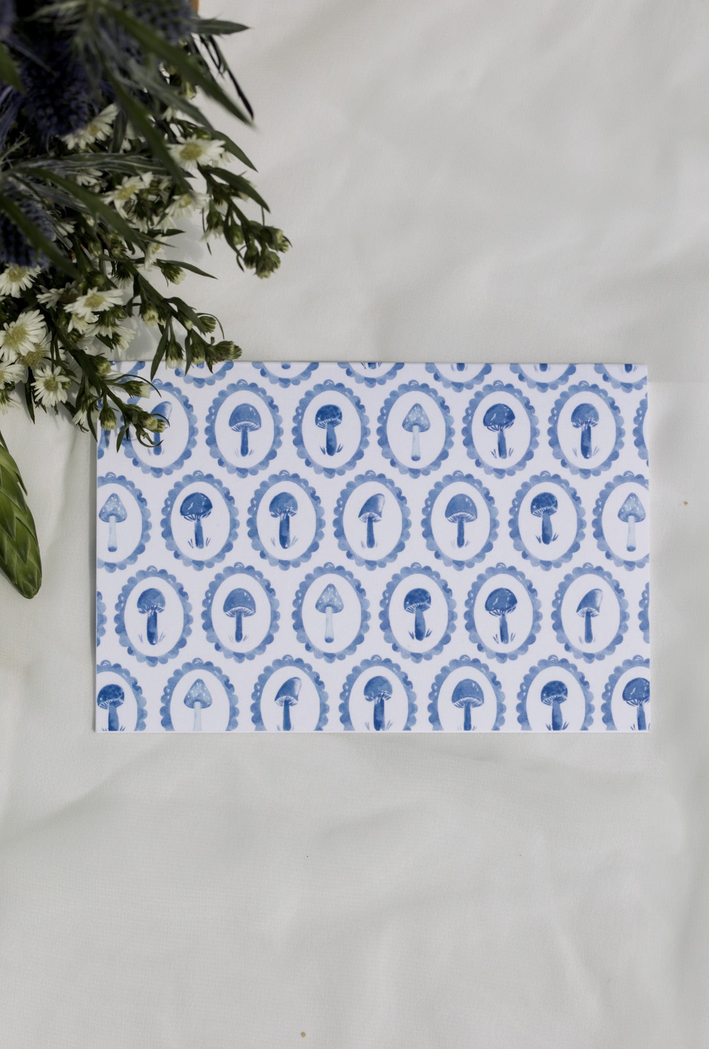 Blue mushroom patterned greeting card with a white background and flower arrangement 