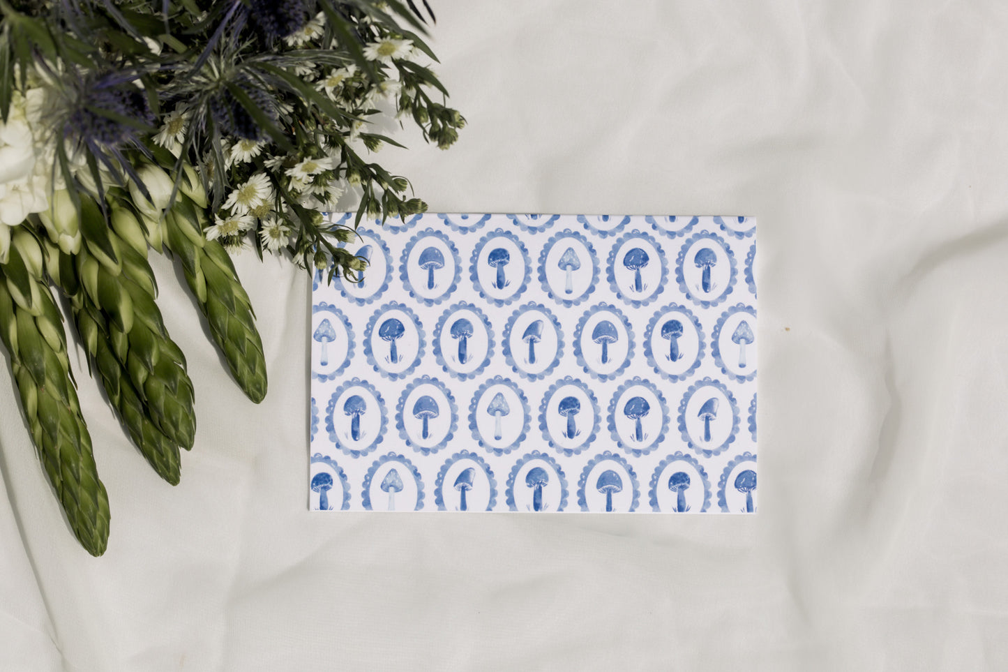 Blue mushroom patterned greeting card with a white background and flower arrangement 
