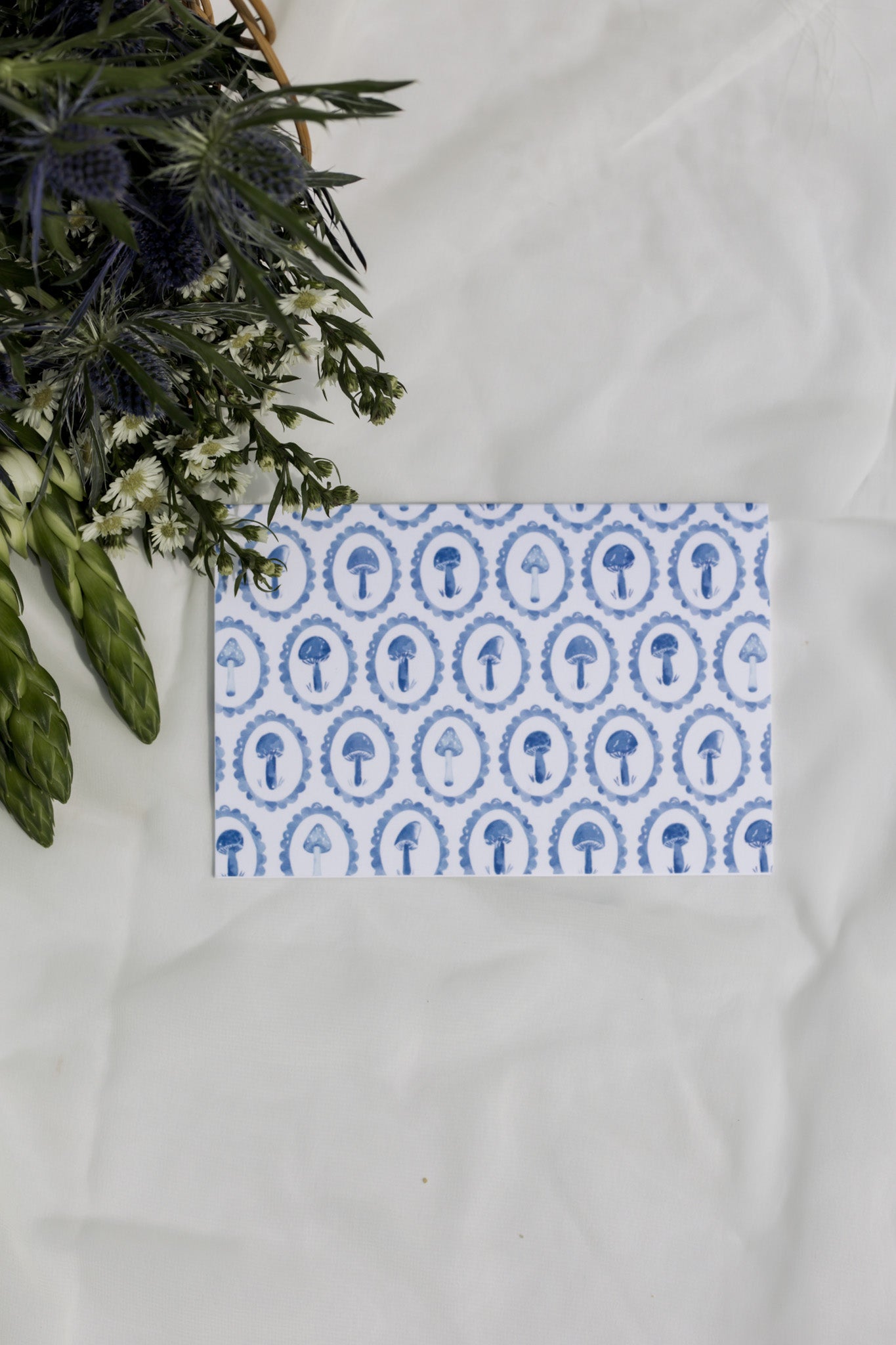 Blue mushroom patterned greeting card with a white background and flower arrangement 