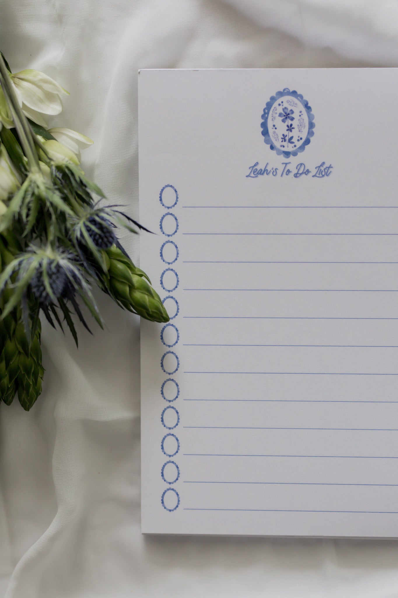 Notepad with floral design and text on a white fabric background