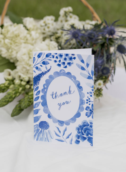 Blue floral card with 'thank you' text and a flower arrangement background