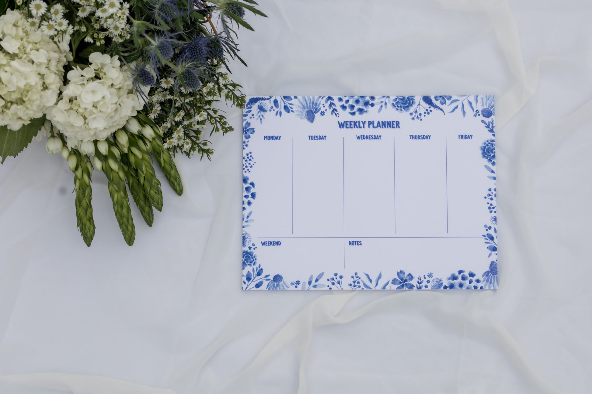 Weekly planner with floral design on a white surface with flowers